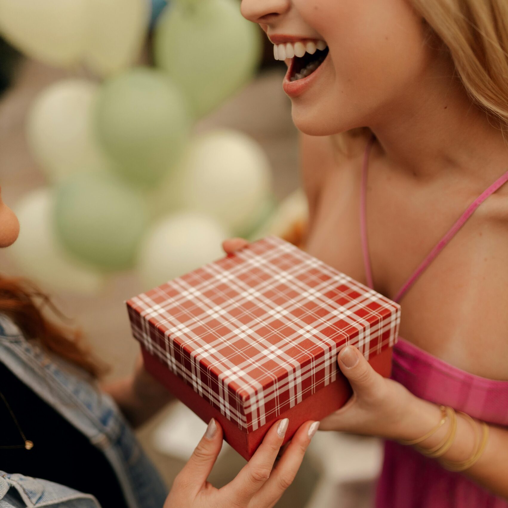 Two women exchange a gift outdoors, creating a warm and joyful moment.